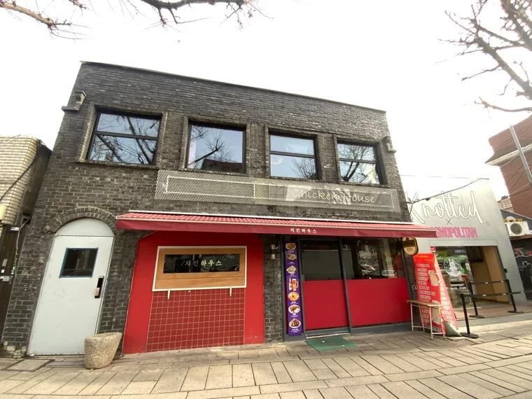 짙은 건물 외벽과 붉은 매장 입구를 담은 완공 후 모습.